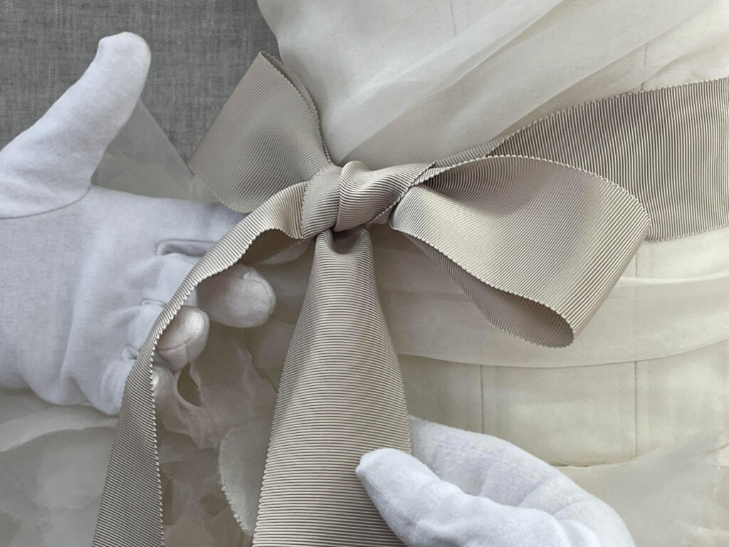 Details including how the sash was originally knotted, were noted when assembling the display - Framing a Vera Wang Gown