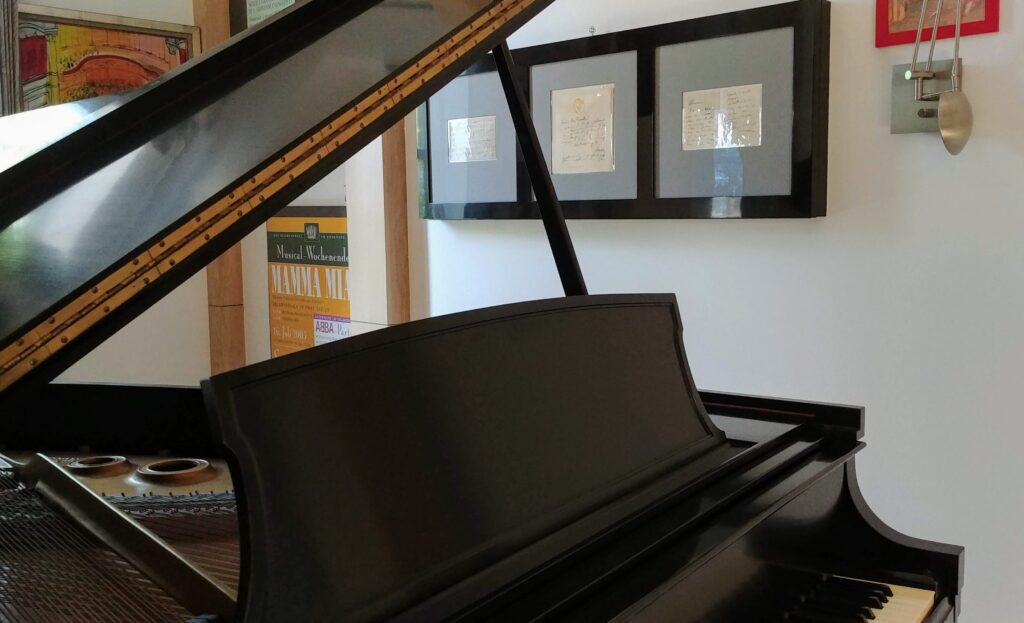 black piano with box framed music sheets and custom cabinets for written music notes
